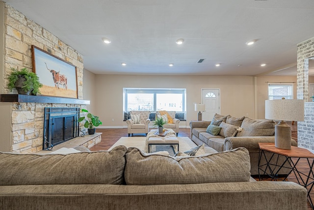 living area with recessed lighting, a healthy amount of sunlight, a stone fireplace, and wood finished floors