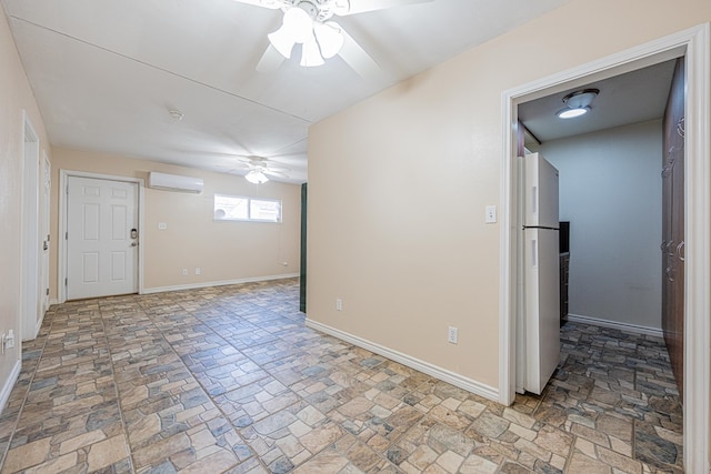 empty room featuring a wall unit AC, baseboards, and a ceiling fan