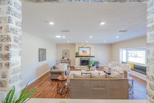 living room with visible vents, a fireplace, a textured ceiling, and wood finished floors