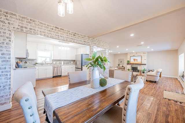 dining room with recessed lighting, light wood-style flooring, baseboards, and a stone fireplace