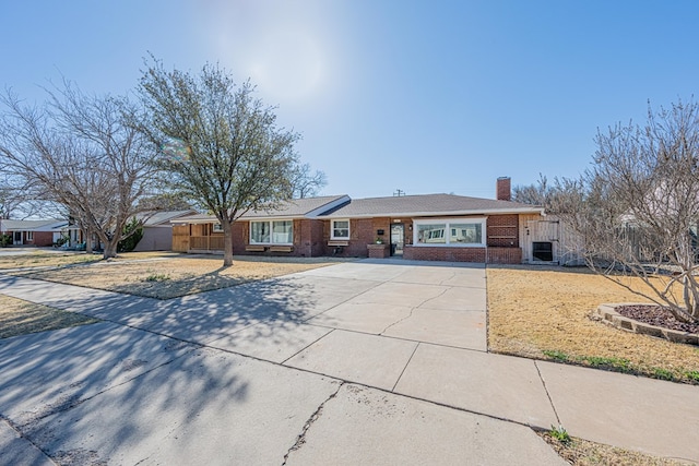 ranch-style house with brick siding, a chimney, and central air condition unit