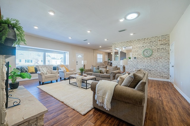 living area featuring recessed lighting, brick wall, dark wood-style flooring, visible vents, and baseboards