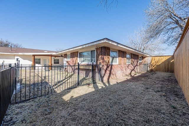 view of front of property with ceiling fan, a patio, brick siding, and a fenced backyard