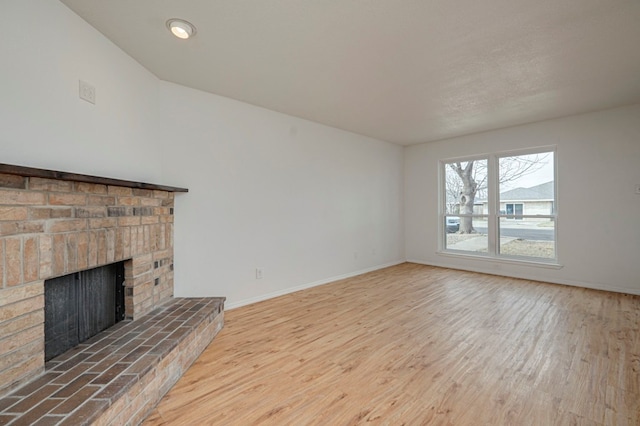 unfurnished living room with a fireplace, baseboards, and wood finished floors