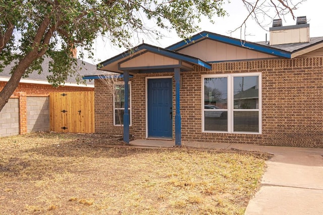 view of front of property featuring brick siding, fence, and a gate