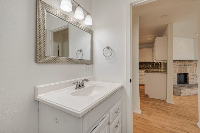 bathroom with a fireplace, wood finished floors, and vanity