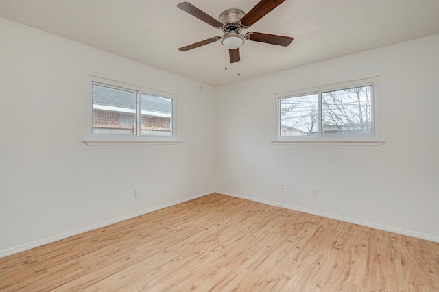 empty room featuring plenty of natural light, baseboards, ceiling fan, and wood finished floors