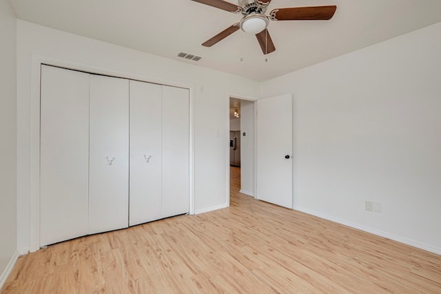 unfurnished bedroom featuring baseboards, a closet, visible vents, and wood finished floors