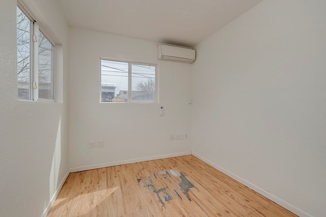 empty room with baseboards, light wood finished floors, and a wall mounted AC