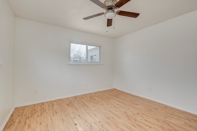 spare room featuring wood finished floors, a ceiling fan, and baseboards