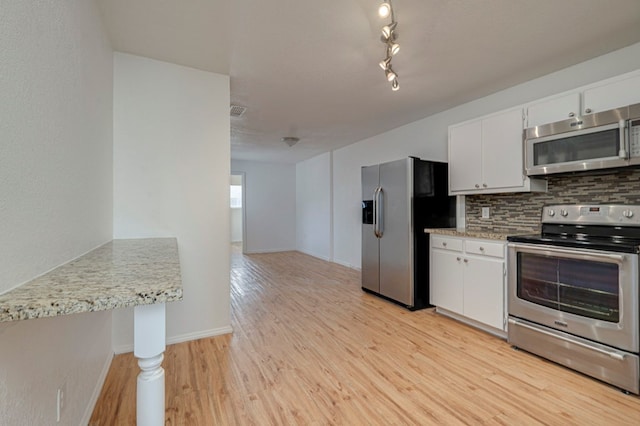 kitchen with stainless steel appliances, light wood finished floors, white cabinets, and decorative backsplash