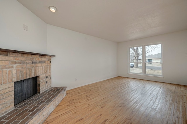 unfurnished living room with a fireplace, baseboards, and wood finished floors