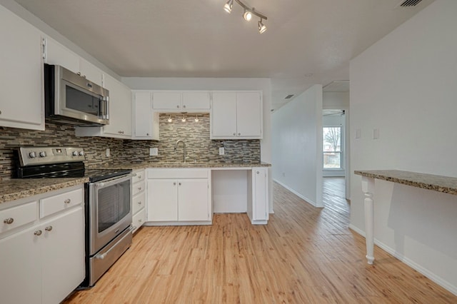 kitchen with tasteful backsplash, white cabinets, light wood-style flooring, appliances with stainless steel finishes, and a sink