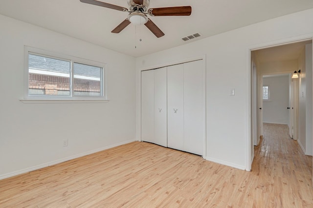 unfurnished bedroom featuring ceiling fan, wood finished floors, visible vents, baseboards, and a closet