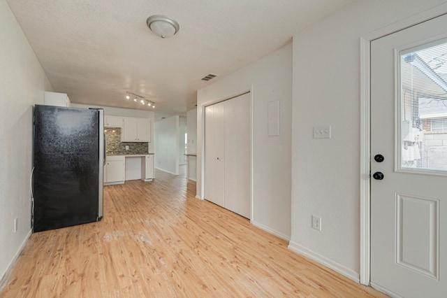 interior space featuring light wood-style floors, baseboards, and visible vents