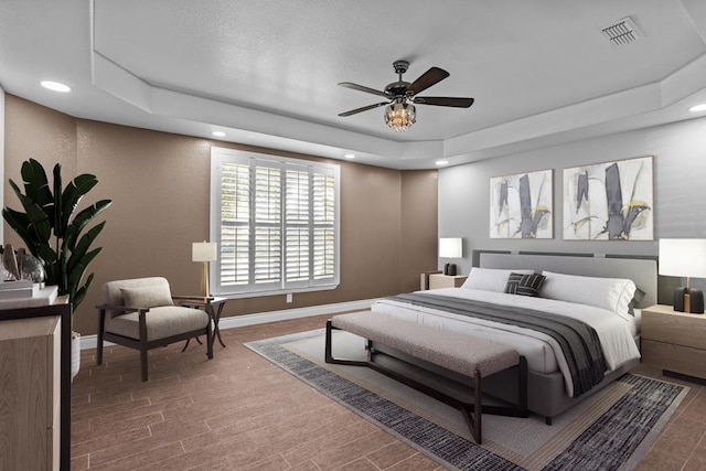 bedroom featuring hardwood / wood-style flooring, ceiling fan, and a tray ceiling