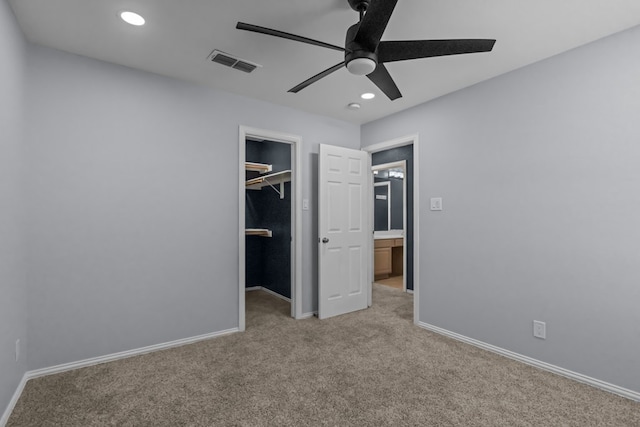 unfurnished bedroom featuring light carpet, a spacious closet, a closet, and ceiling fan