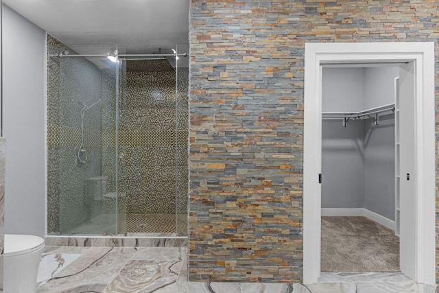 bathroom featuring a shower with door and toilet