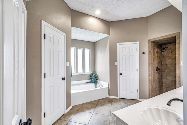 full bath with a textured ceiling, tile patterned flooring, a tile shower, a bath, and vanity