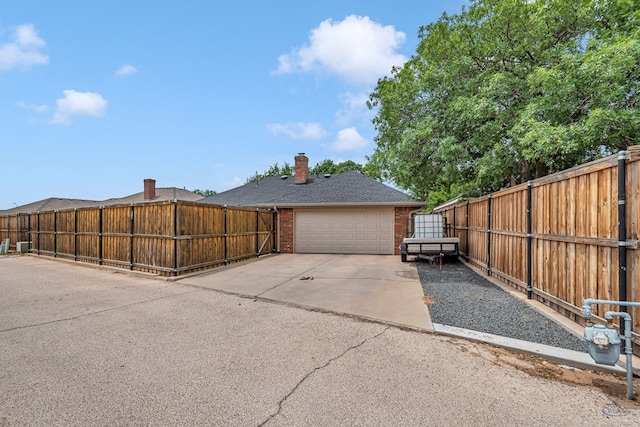view of side of home with brick siding, fence, driveway, and a chimney