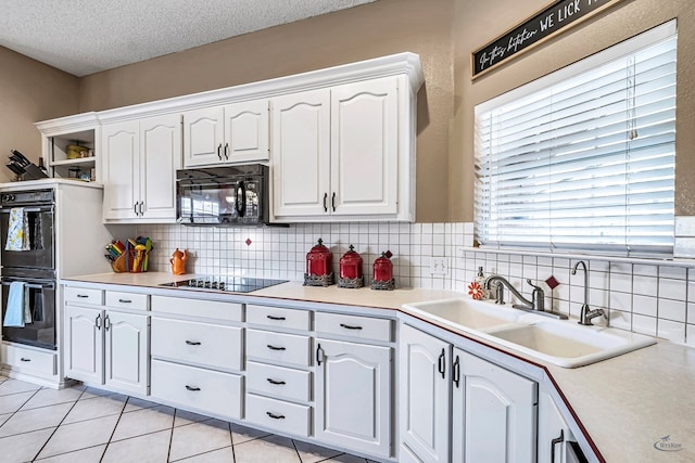 kitchen featuring black appliances, white cabinets, a sink, decorative backsplash, and a textured ceiling
