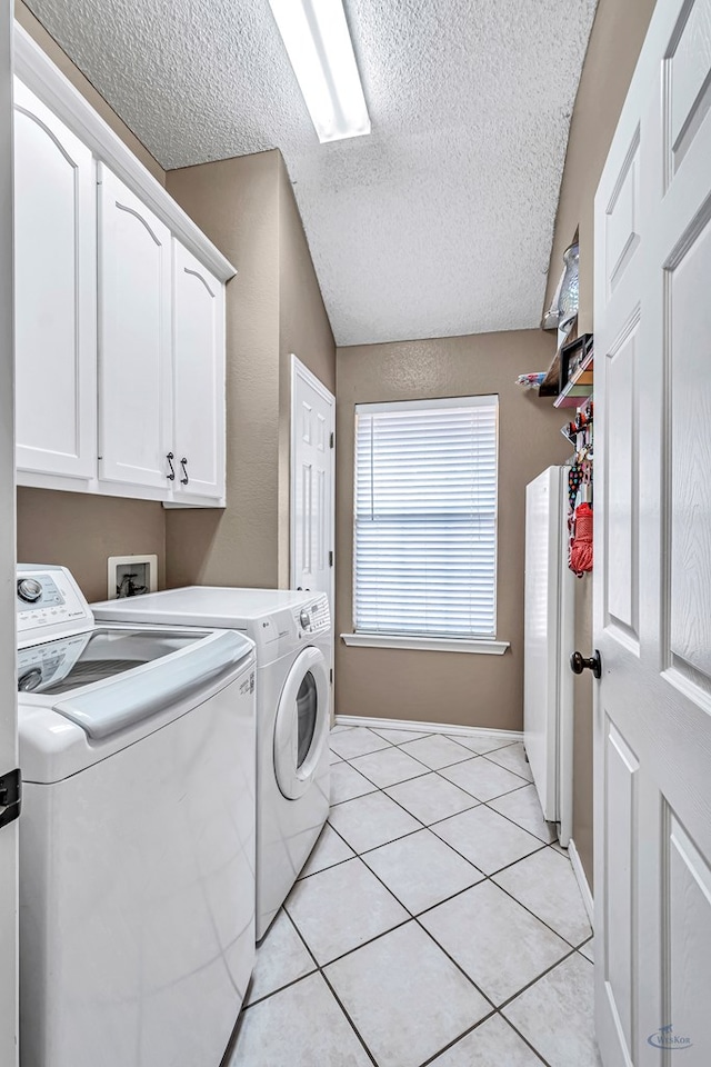 laundry room with washer and clothes dryer, cabinet space, a textured ceiling, and light tile patterned flooring