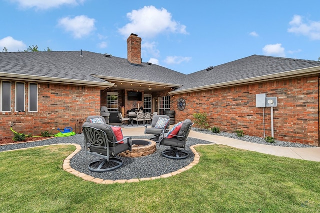 back of property with a fire pit, roof with shingles, brick siding, and a chimney