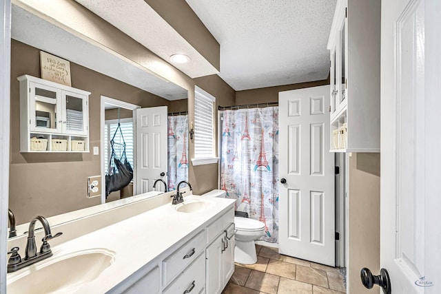 full bathroom featuring toilet, double vanity, a shower with curtain, and a textured ceiling