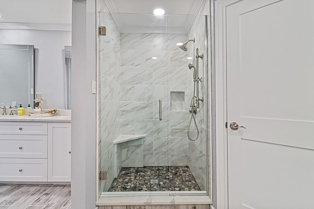 bathroom featuring wood-type flooring, vanity, a shower with shower door, and crown molding