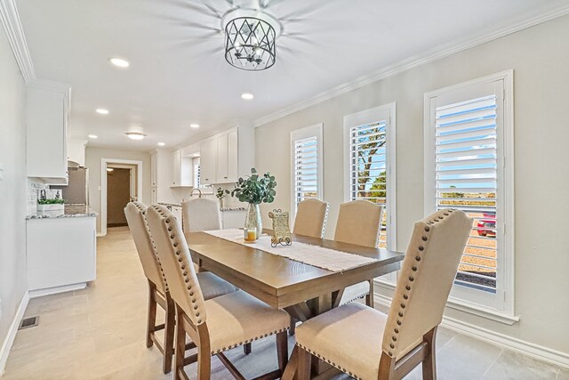 tiled dining area with a chandelier and crown molding