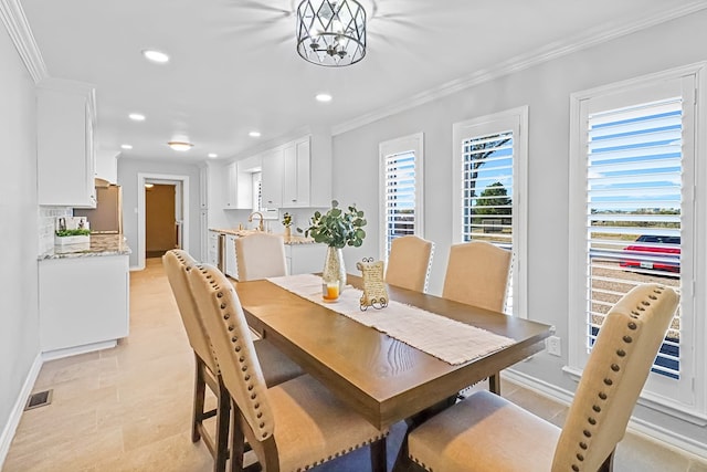 dining space featuring crown molding, sink, and a chandelier