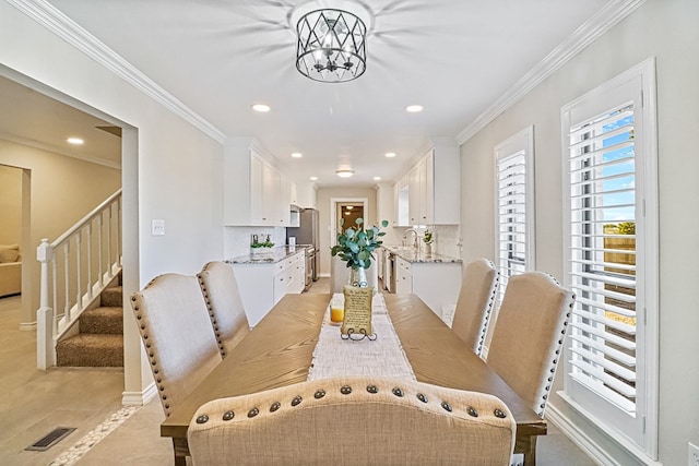 tiled dining space featuring crown molding, sink, and a chandelier