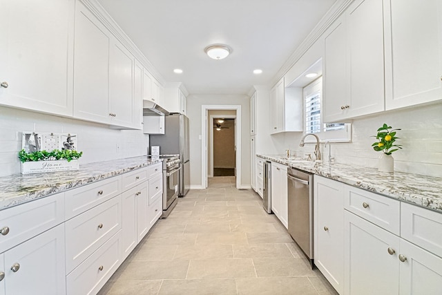 kitchen featuring light stone countertops, tasteful backsplash, stainless steel appliances, sink, and white cabinets