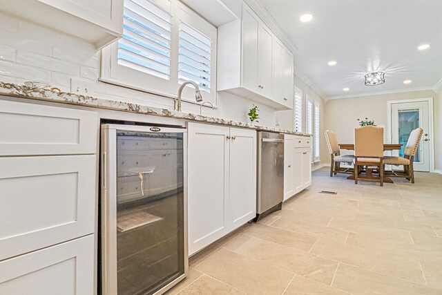 kitchen with white cabinets, sink, light stone countertops, ornamental molding, and beverage cooler