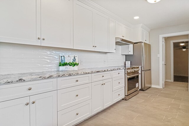 kitchen with white cabinets, light stone counters, high end stainless steel range, and tasteful backsplash