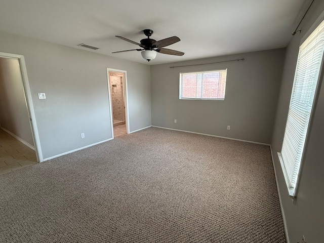 carpeted spare room featuring a ceiling fan and baseboards