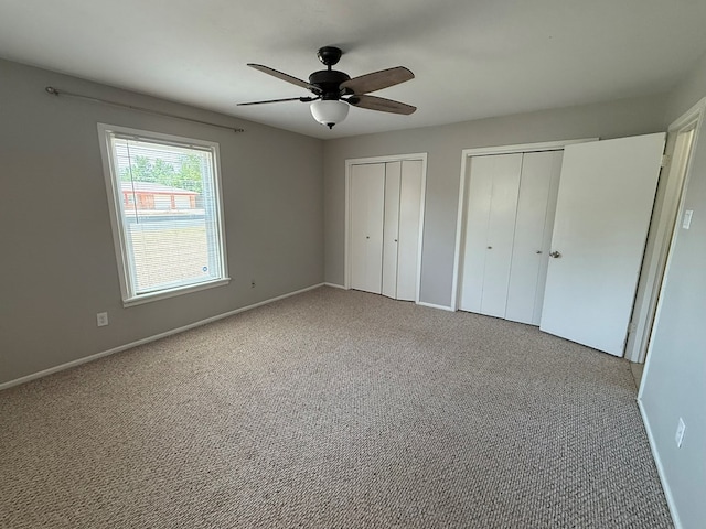 unfurnished bedroom featuring two closets, baseboards, and carpet floors