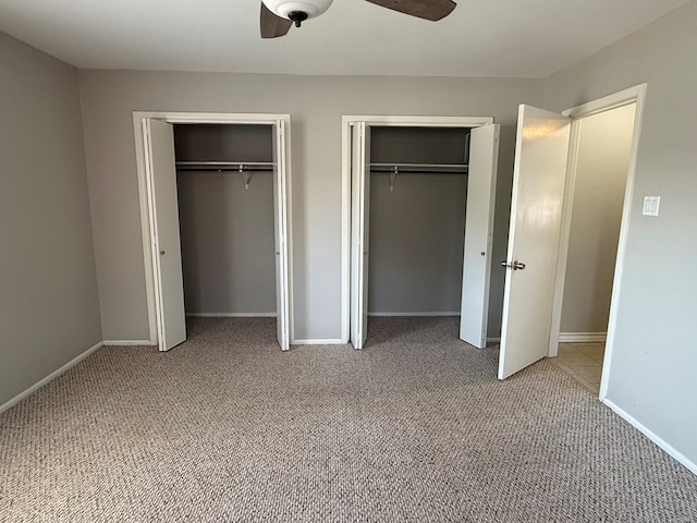 unfurnished bedroom featuring two closets, light colored carpet, baseboards, and a ceiling fan