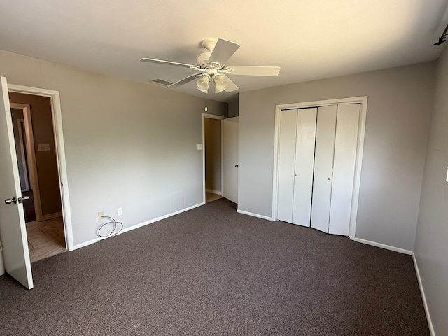 unfurnished bedroom featuring dark colored carpet, a closet, baseboards, and ceiling fan
