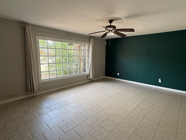 tiled spare room with ceiling fan and baseboards