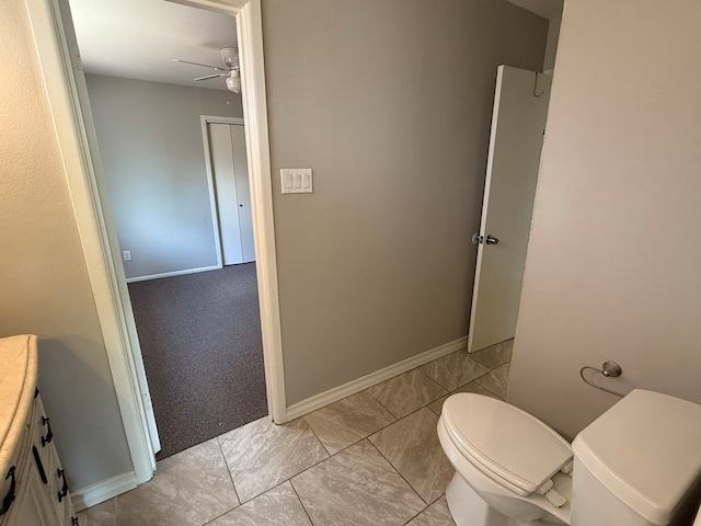 bathroom with toilet, a ceiling fan, vanity, and baseboards