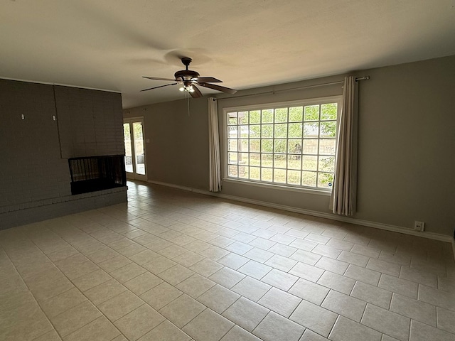 unfurnished living room with tile patterned flooring, a ceiling fan, baseboards, and a brick fireplace