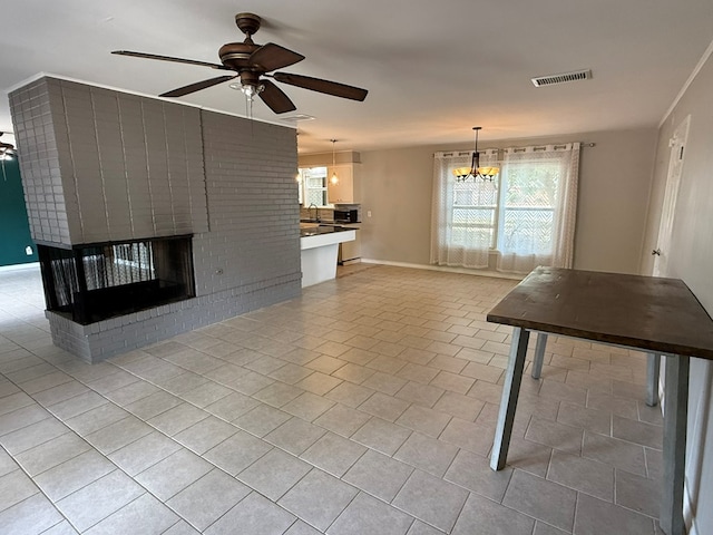 unfurnished living room with a ceiling fan, healthy amount of natural light, light tile patterned flooring, and a chandelier