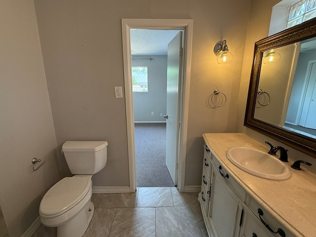half bathroom with baseboards, vanity, and toilet