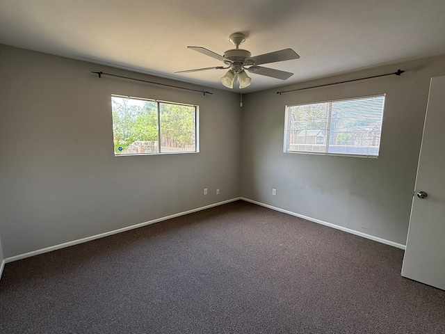 unfurnished room featuring ceiling fan, dark carpet, and baseboards