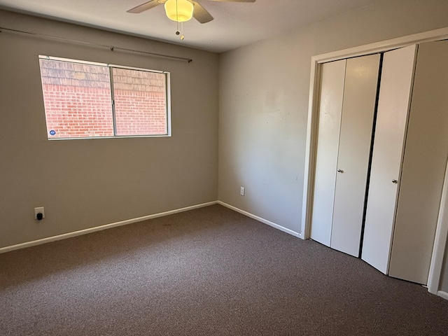 unfurnished bedroom with dark carpet, a closet, baseboards, and ceiling fan