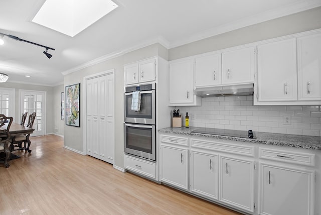1426 Lanham St, Midland, TX 79701 - kitchen featuring double oven, black electric cooktop, under cabinet range hood, tasteful backsplash, and crown molding