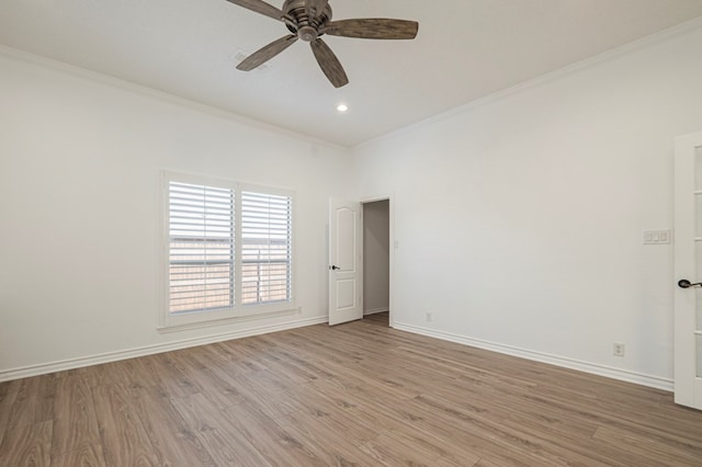 spare room featuring ornamental molding, light wood-type flooring, baseboards, and a ceiling fan