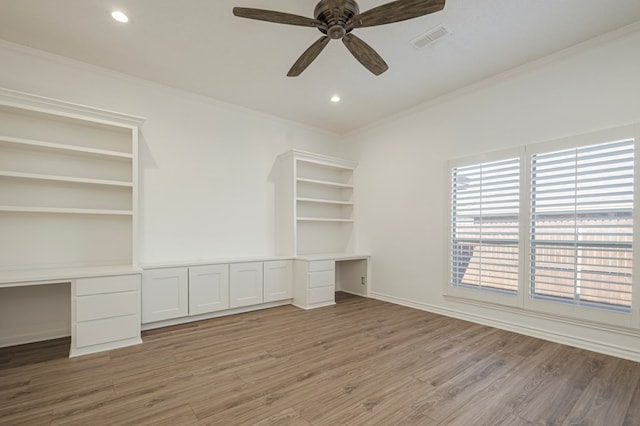 unfurnished office featuring visible vents, wood finished floors, crown molding, and built in study area