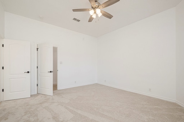 spare room with ceiling fan, lofted ceiling, light colored carpet, visible vents, and baseboards